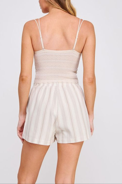 Woman wearing a beige romper with thin straps on a white background