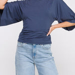 Woman wearing a blue top and jeans on a white background