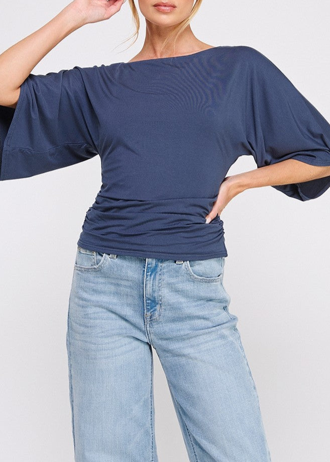 Woman wearing a blue top and jeans on a white background