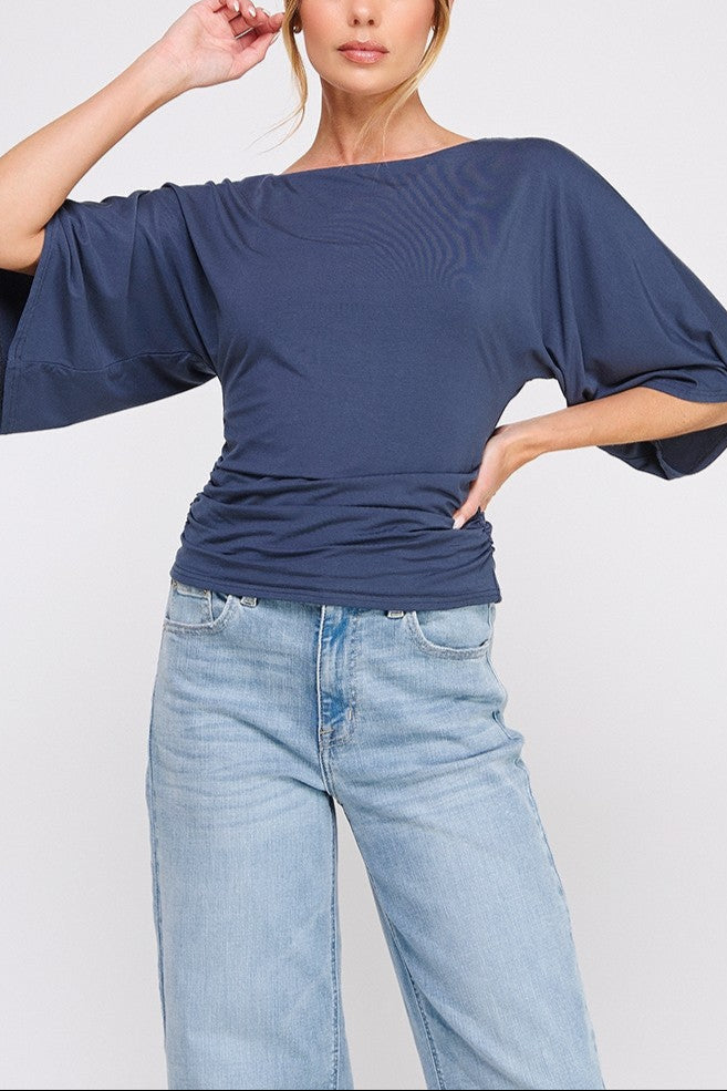 Woman wearing a blue top and jeans on a white background