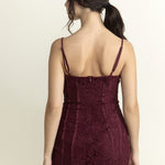 Woman wearing a burgundy lace dress against a beige background
