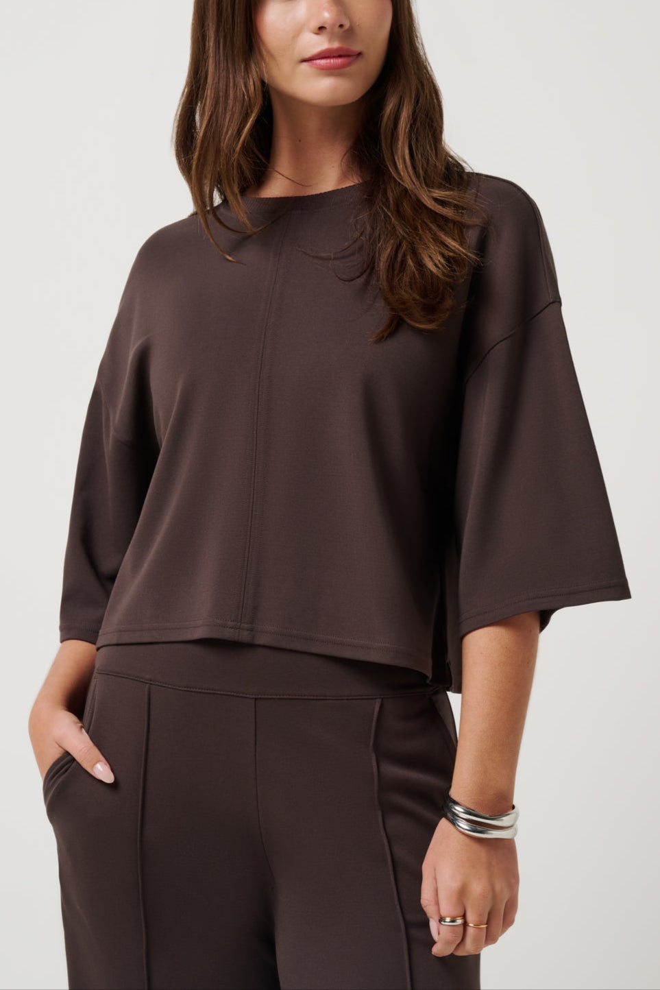 Woman wearing a brown blouse and pants on a white background