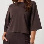 Woman wearing a brown blouse and pants on a white background