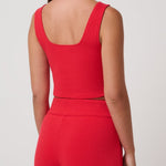 Woman wearing a red sleeveless top and pants on a white background