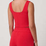 Woman wearing a red sleeveless top and pants on a white background