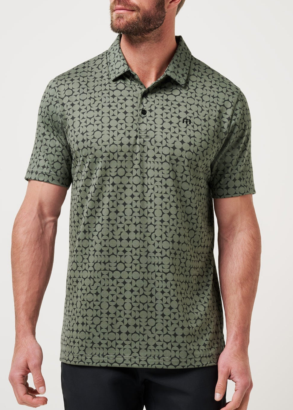 Man wearing a green patterned polo shirt against a white background