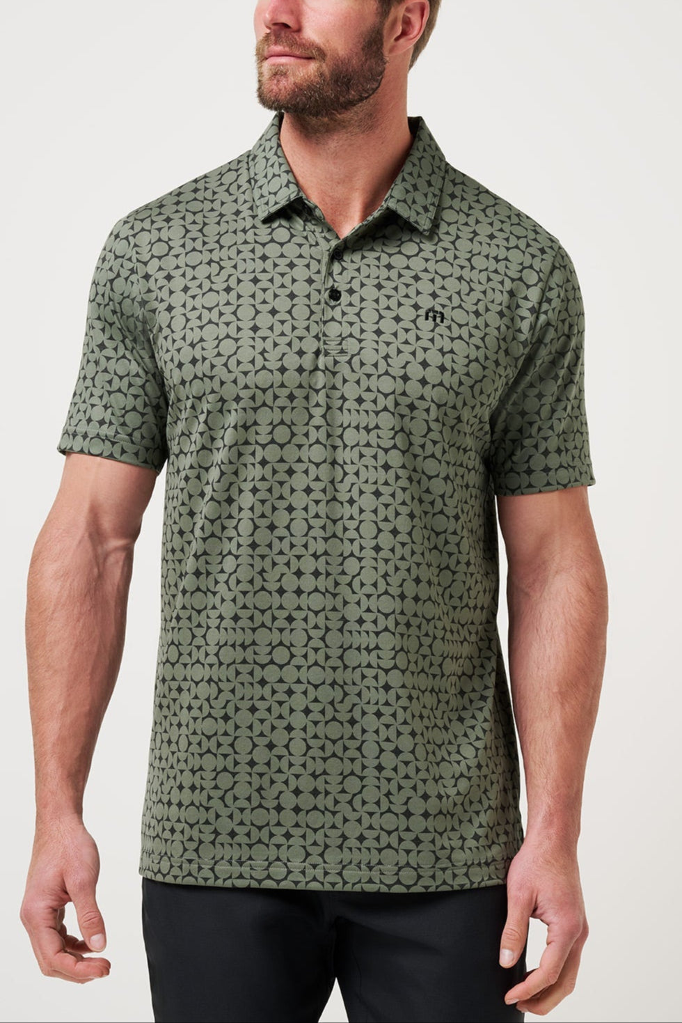 Man wearing a green patterned polo shirt against a white background