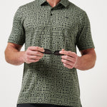 Man wearing a green patterned shirt holding sunglasses against a white background