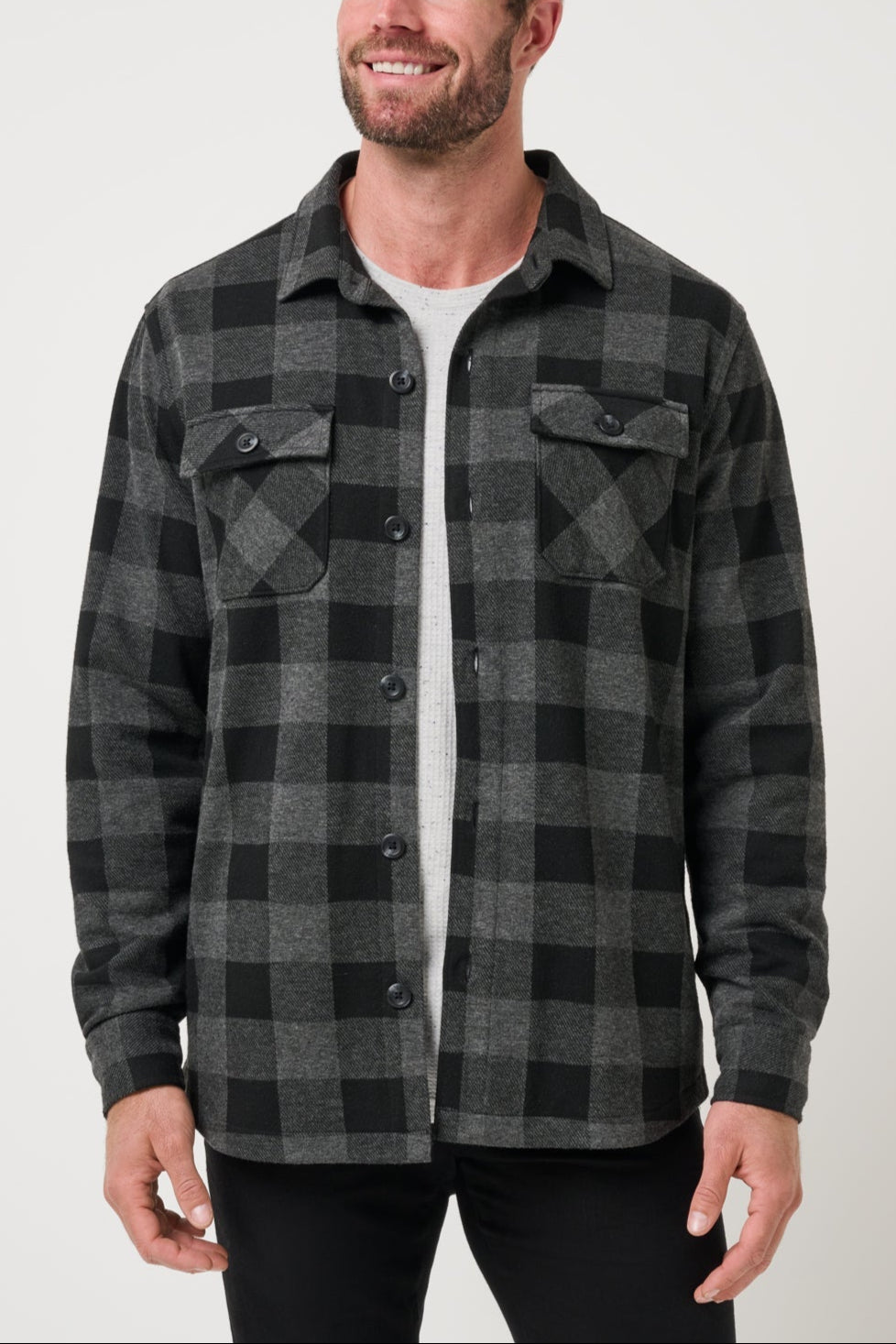 Man wearing a gray and black plaid shirt against a white background