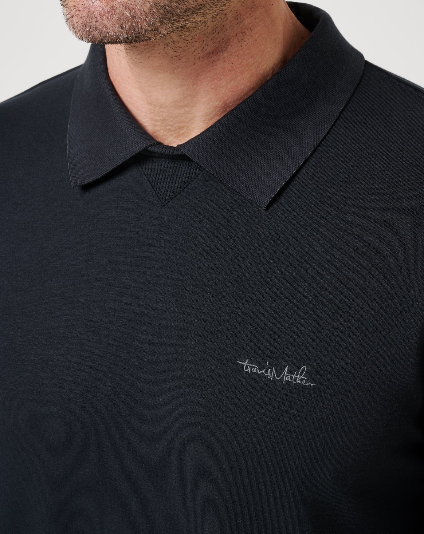 Black polo shirt with a brand logo on a plain background