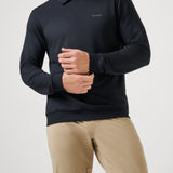 Man wearing a black long-sleeve polo shirt and beige pants on a light gray background