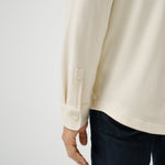 Beige long-sleeve shirt worn by a person on a white background