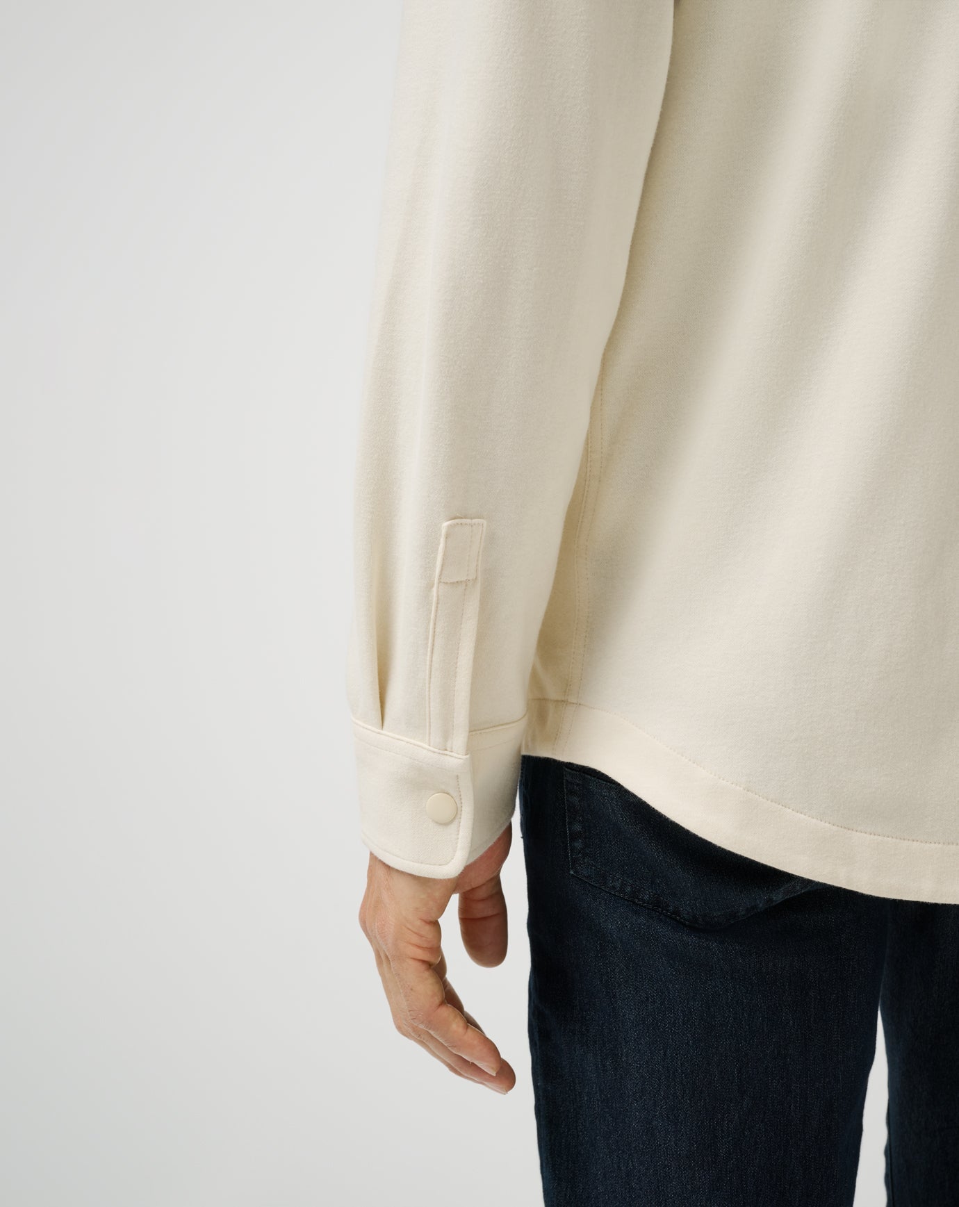 Beige long-sleeve shirt worn by a person on a white background