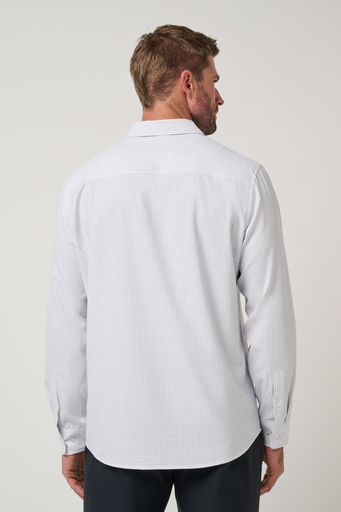 Travis Mathew Techwoven Cross Check Button-Up in White, back view showing curved hem
