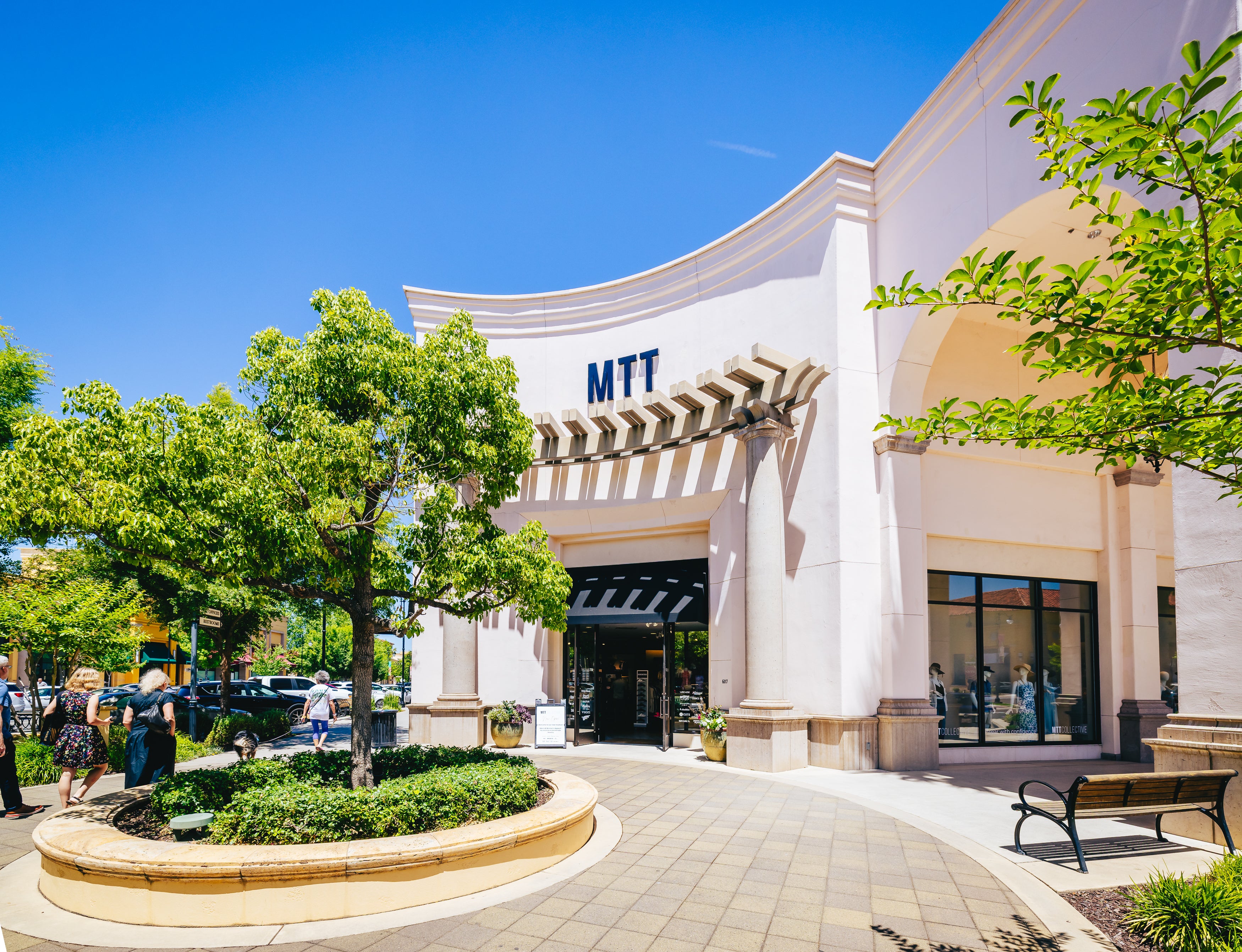 MTT Collective storefront with a clear blue sky and green trees