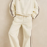 Woman wearing a cream-colored outfit with black trim against a beige background