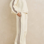 Woman wearing a white outfit with black stripes against a beige background