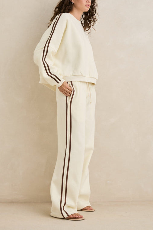 Woman wearing a white outfit with black stripes against a beige background