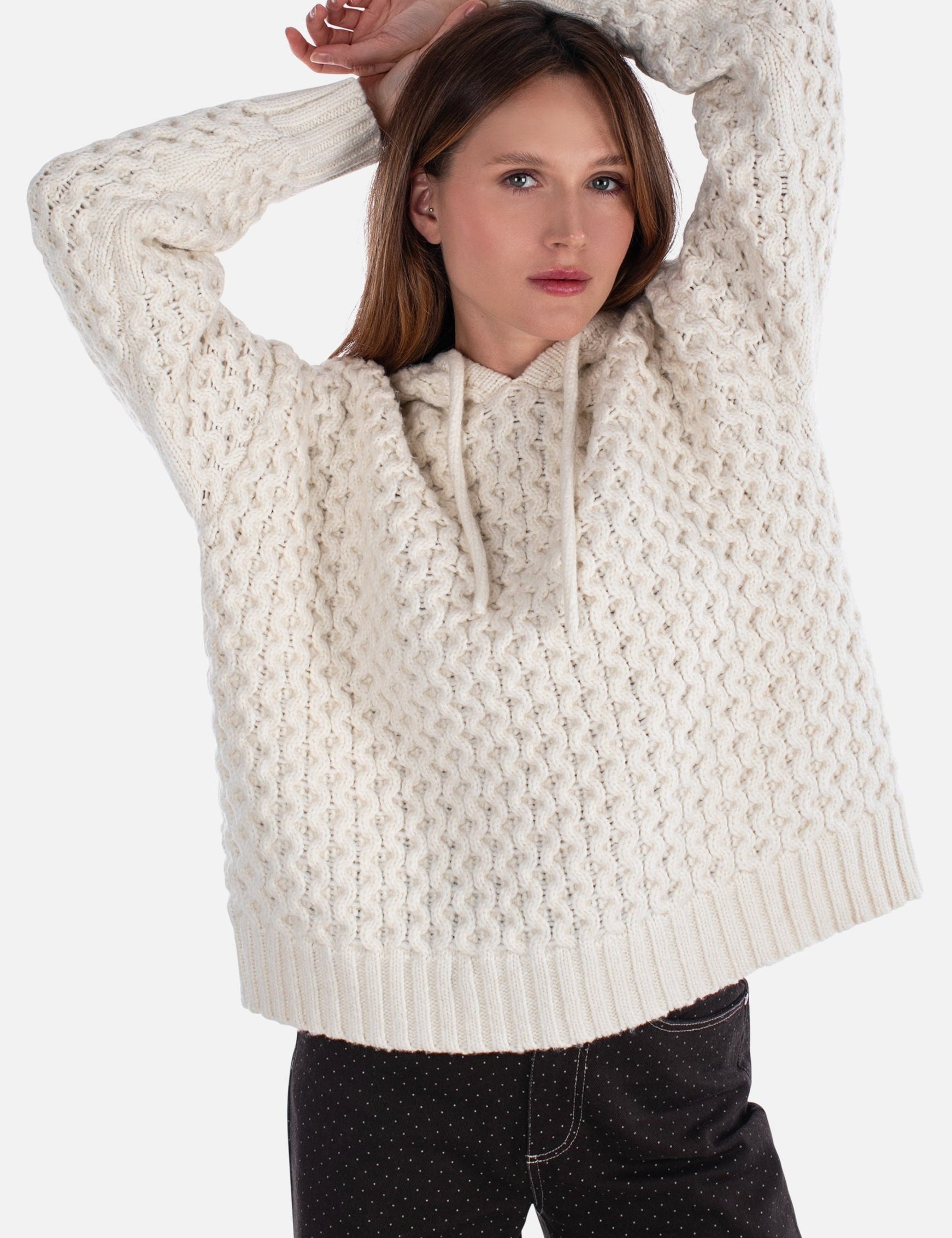Woman wearing a cream knitted sweater on a white background