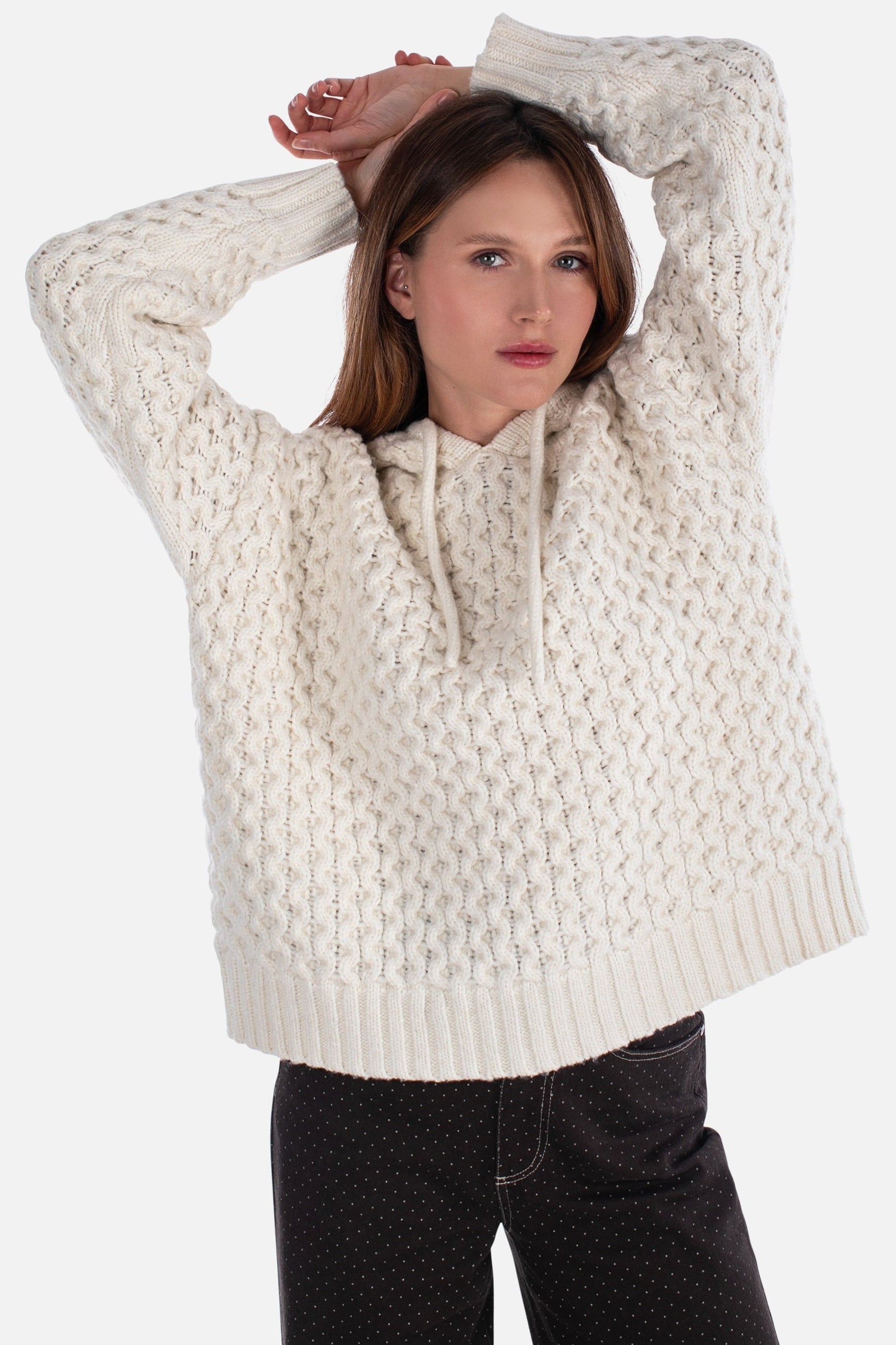 Woman wearing a cream knitted sweater on a white background