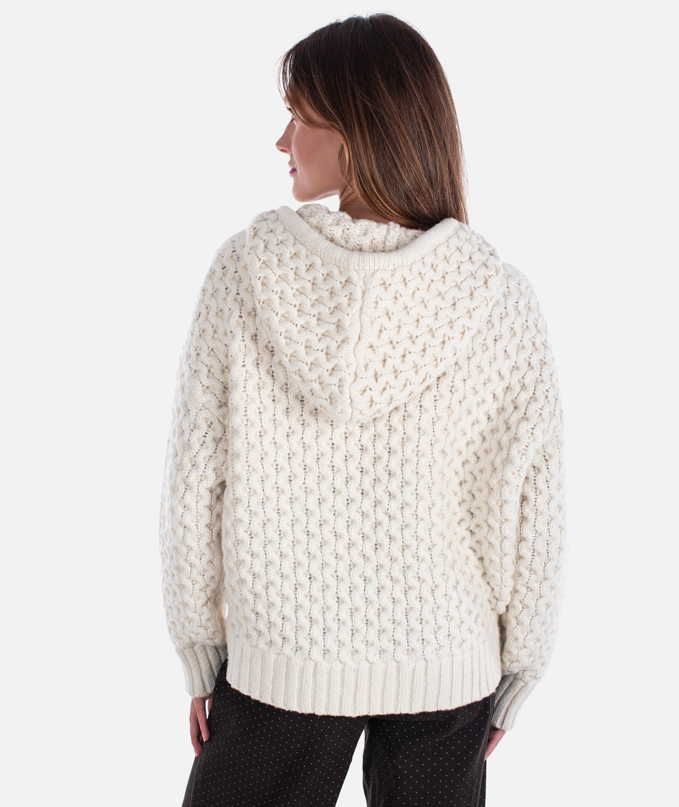 Woman wearing a cream knitted sweater on a white background