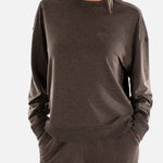 Woman wearing a brown sweatshirt and pants on a white background