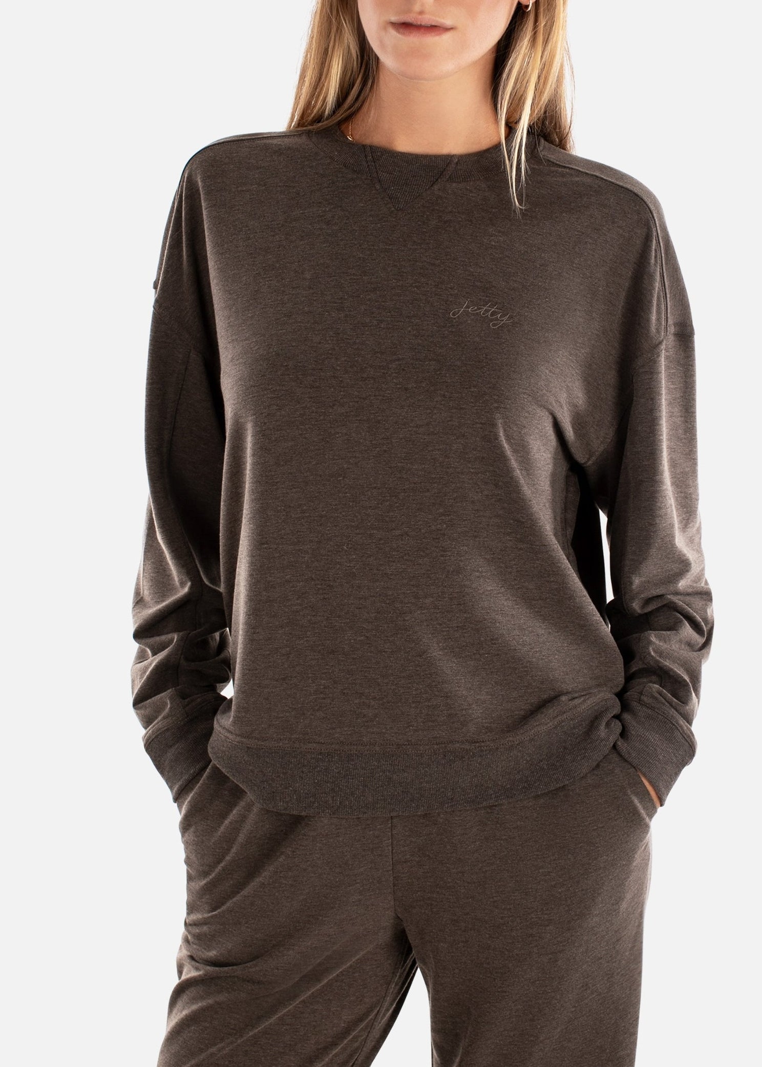 Woman wearing a brown sweatshirt and pants on a white background