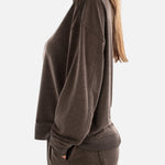 Woman wearing a brown sweatshirt and pants on a white background
