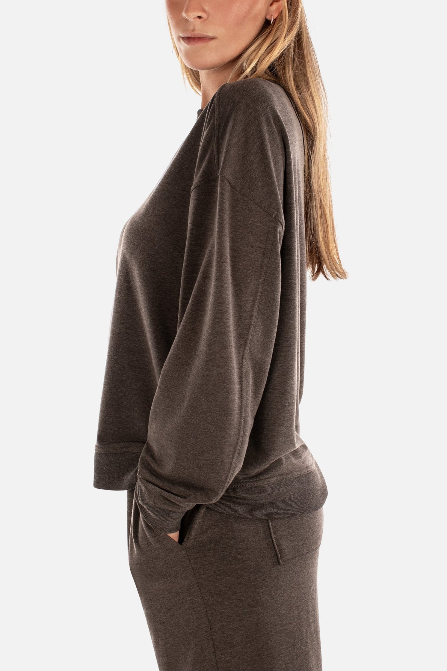 Woman wearing a brown sweatshirt and pants on a white background