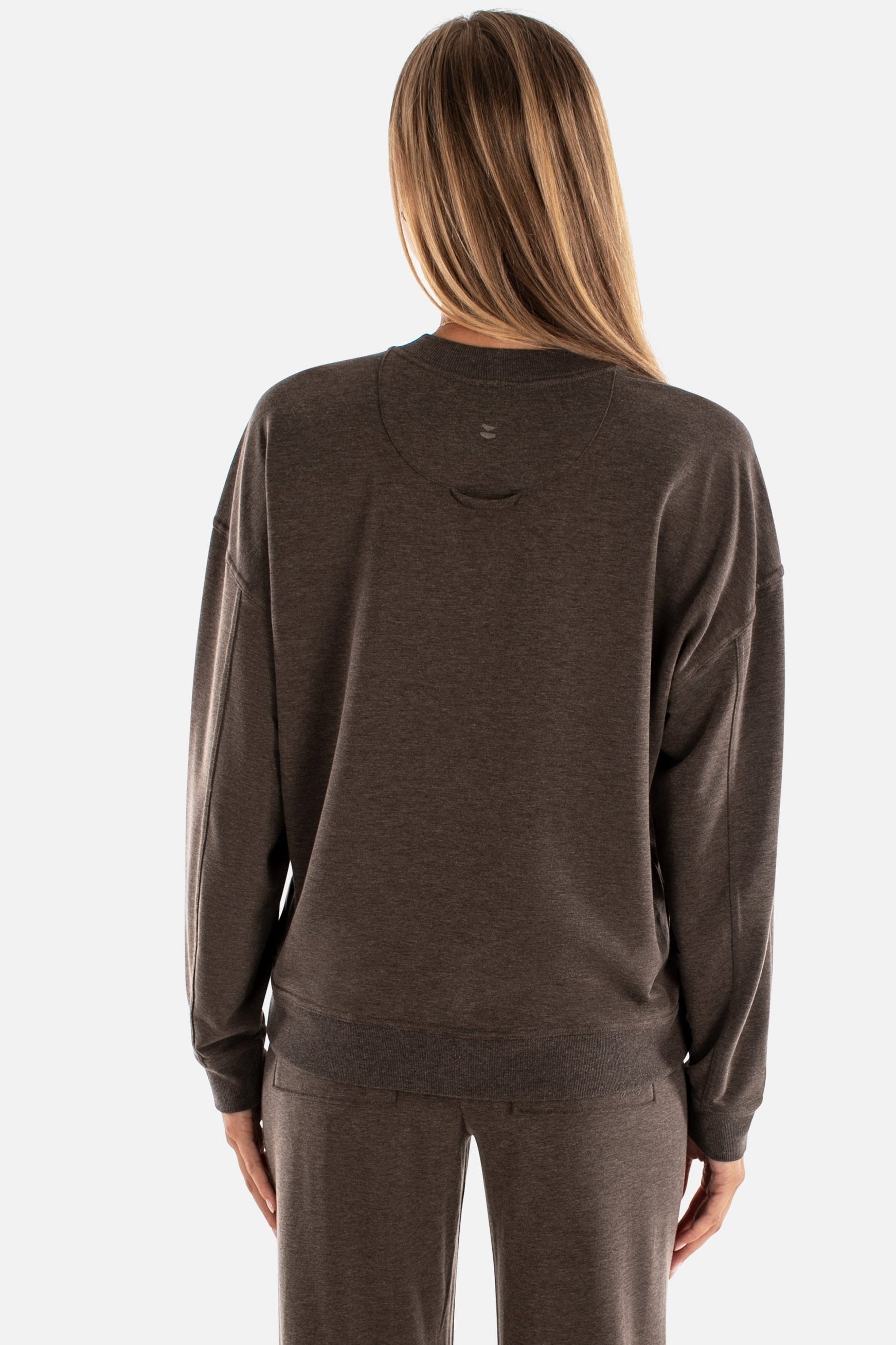 Person wearing a brown sweatshirt and pants on a white background