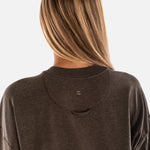 Person wearing a brown hoodie with a visible brand logo on a white background