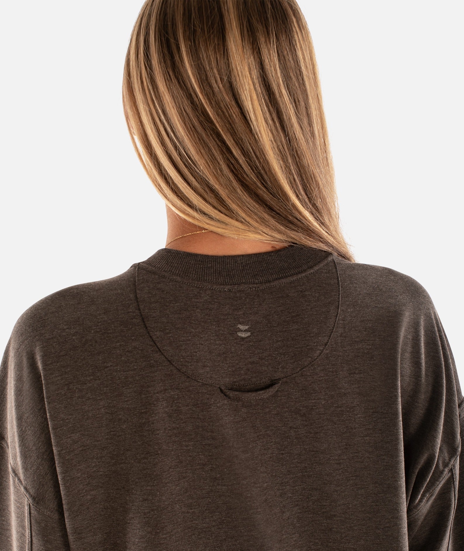 Person wearing a brown hoodie with a visible brand logo on a white background
