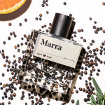 Guy Fox Marra cologne bottle flat lay with black peppercorns and citrus