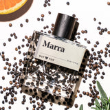 Guy Fox Marra cologne bottle flat lay with black peppercorns and citrus
