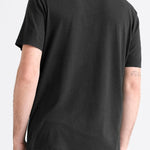 Man wearing a black t-shirt and blue jeans on a light gray background