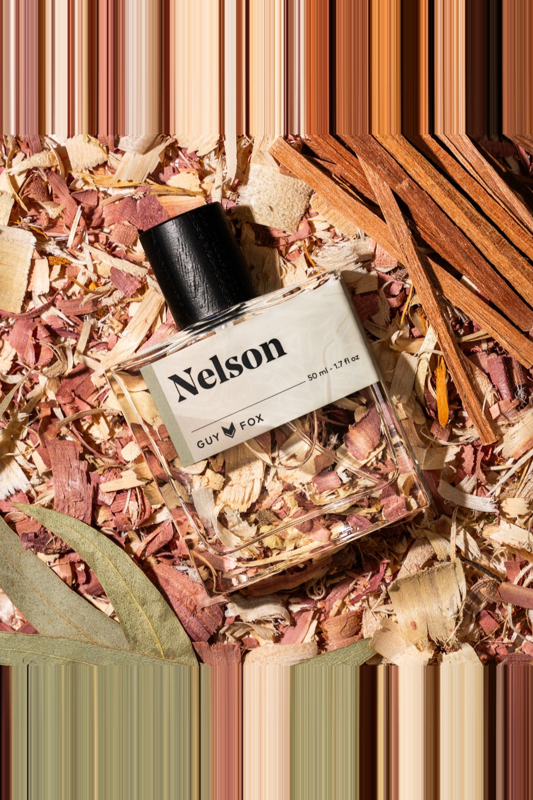 Guy Fox Nelson cologne bottle flat lay with cedar wood shavings