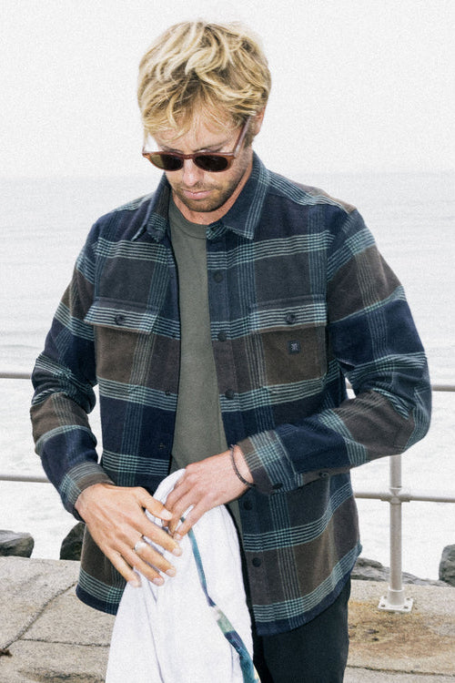 Man wearing a plaid shirt by a waterfront