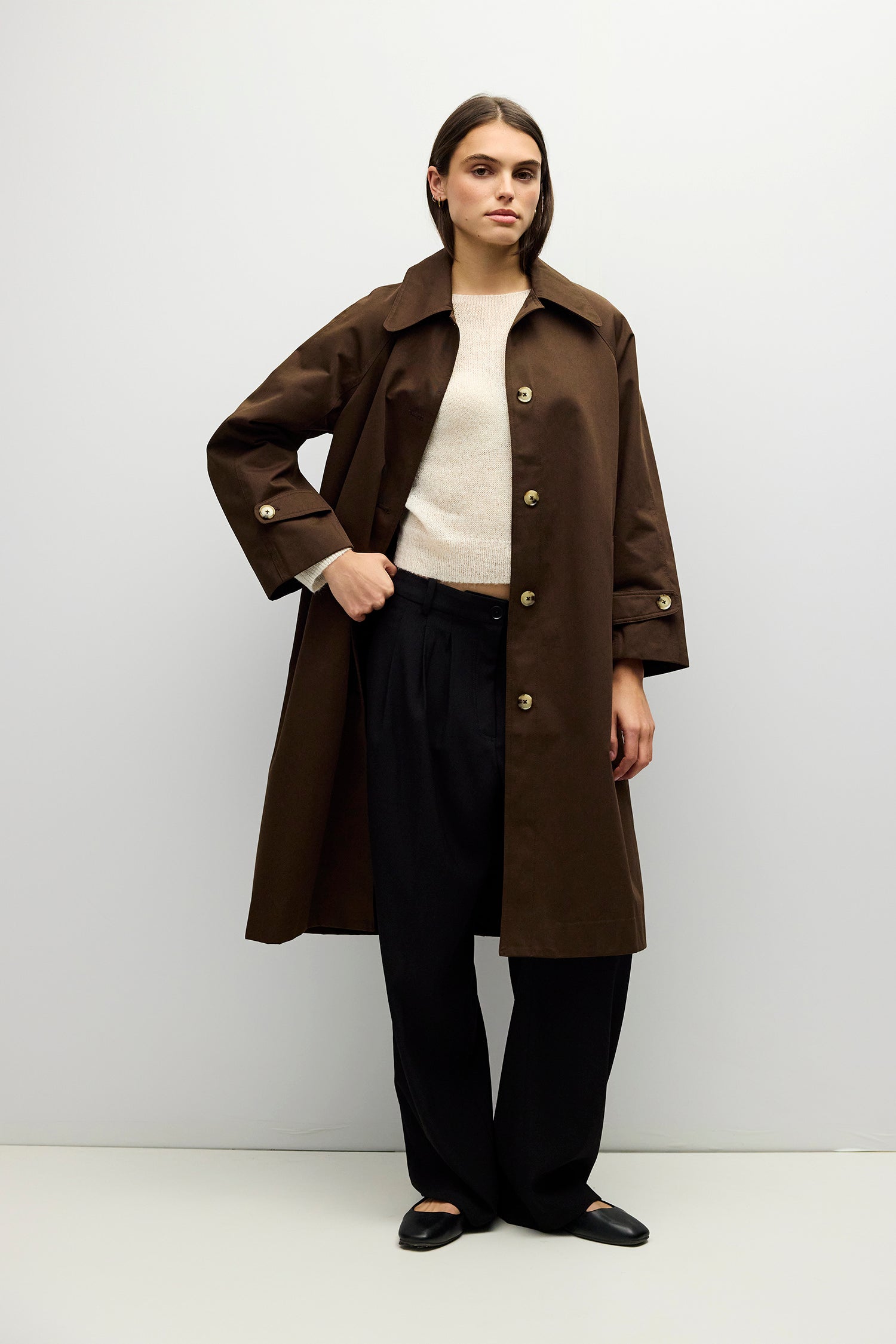 Brown midi trench coat worn open over a knit top