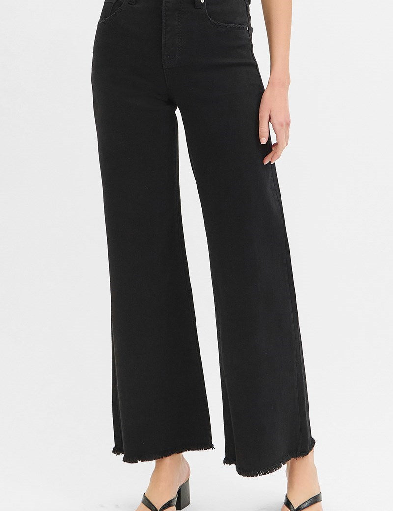 Black wide-leg jeans worn by a person on a white background