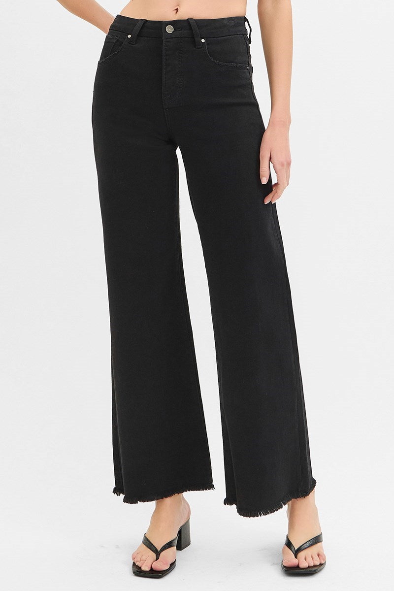 Black wide-leg jeans worn by a person on a white background