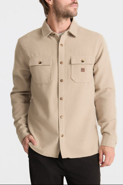 Man wearing a beige button-up shirt on a light gray background