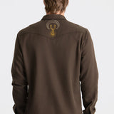Brown shirt with a logo on the back worn by a person against a white background
