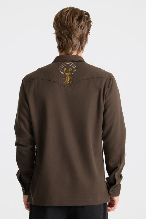 Brown shirt with a logo on the back worn by a person against a white background