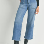 Person wearing high-waisted blue jeans and black boots on a plain background