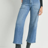 Person wearing high-waisted blue jeans and black boots on a plain background