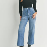 Woman wearing a black turtleneck and blue jeans on a white background