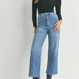 Woman wearing a black turtleneck and blue jeans on a white background