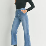 Woman wearing a black turtleneck, blue jeans, and black boots on a white background