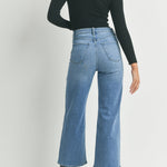 Person wearing blue jeans and a black top on a white background
