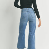 Person wearing blue jeans and a black top on a white background